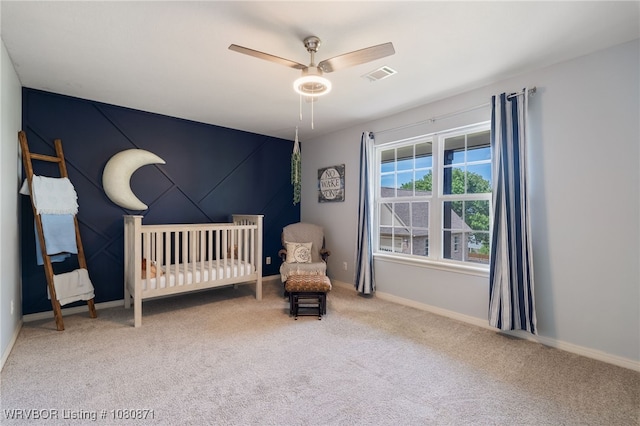 bedroom featuring carpet flooring, baseboards, a crib, and a ceiling fan