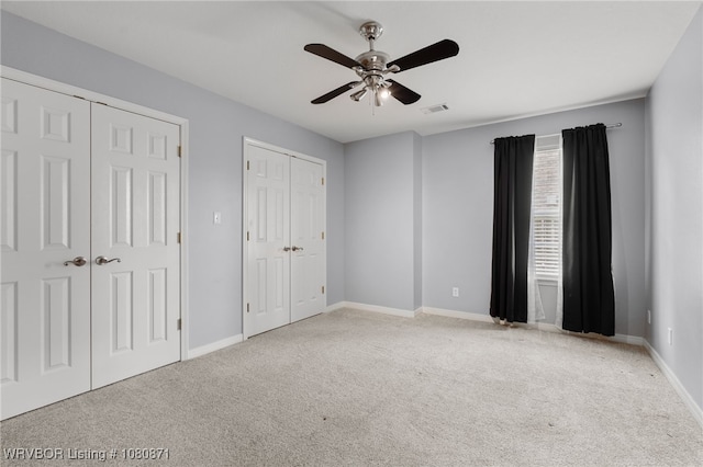 unfurnished bedroom with multiple closets, carpet floors, and baseboards