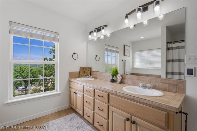 bathroom featuring double vanity, baseboards, and tile patterned flooring