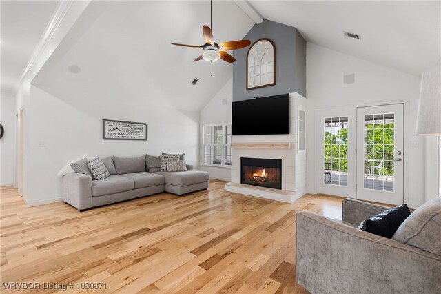 living room featuring high vaulted ceiling, a ceiling fan, wood finished floors, beam ceiling, and a glass covered fireplace