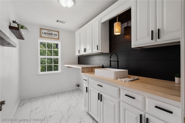laundry room featuring light marble finish floors, baseboards, and cabinet space