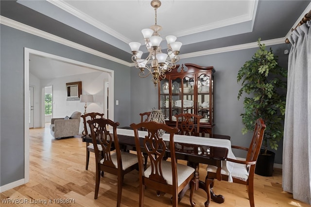 dining space featuring a chandelier, light wood-style floors, baseboards, and crown molding