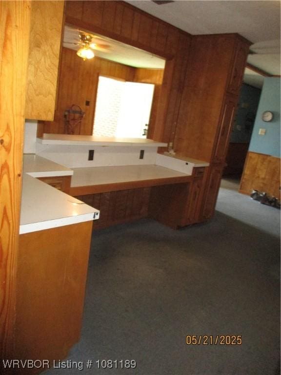 1501 18th St, Ozark, AR 72949 - kitchen with a ceiling fan, wood walls, carpet flooring, and brown cabinetry