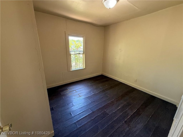 spare room with dark wood-style flooring and baseboards