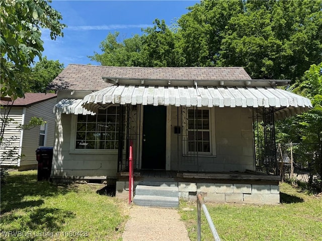 bungalow-style home with roof with shingles and a front lawn
