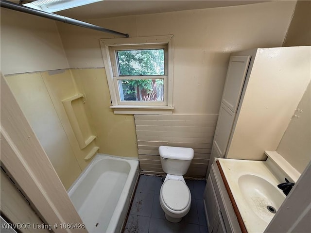 full bath with tile patterned floors, toilet, vanity, and a wainscoted wall
