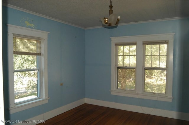 unfurnished room featuring plenty of natural light, dark hardwood / wood-style flooring, ornamental molding, and a chandelier