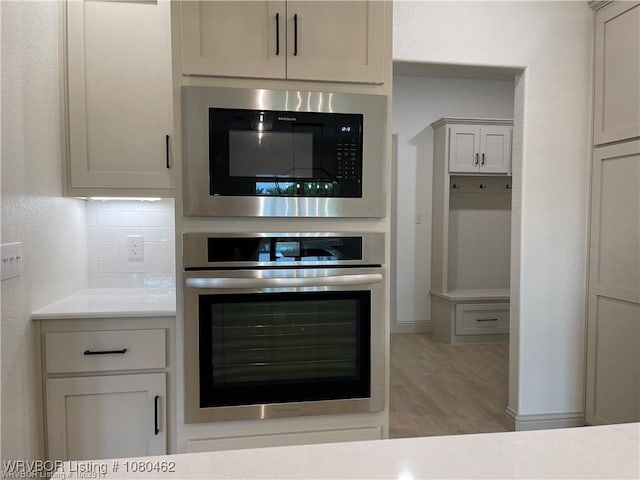 9121 Wayne Xing, Fort Smith, AR 72916 - kitchen featuring stainless steel oven, built in microwave, light wood-style floors, light countertops, and decorative backsplash