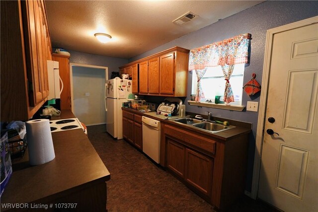 kitchen featuring a textured ceiling, white appliances, and sink