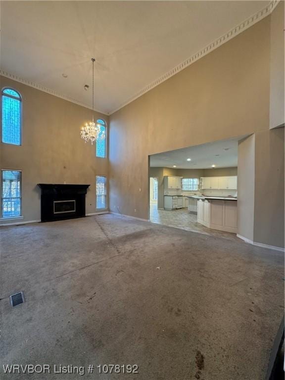 unfurnished living room featuring ornamental molding, a chandelier, and a high ceiling