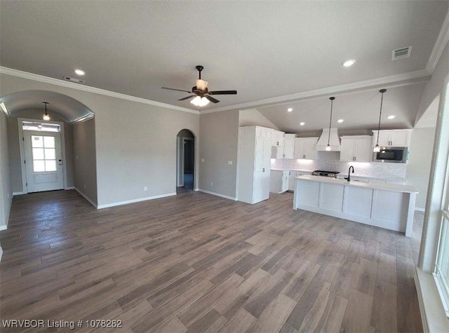 kitchen with stainless steel microwave, vaulted ceiling, hanging light fixtures, white cabinetry, and tasteful backsplash