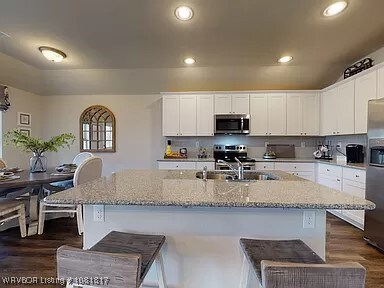 8011 Windflower Ln, Fort Smith, AR 72916 - kitchen featuring stainless steel appliances, dark wood finished floors, white cabinetry, light stone counters, and recessed lighting