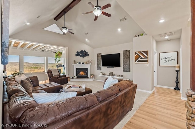 living room with high vaulted ceiling, beam ceiling, and light hardwood / wood-style flooring