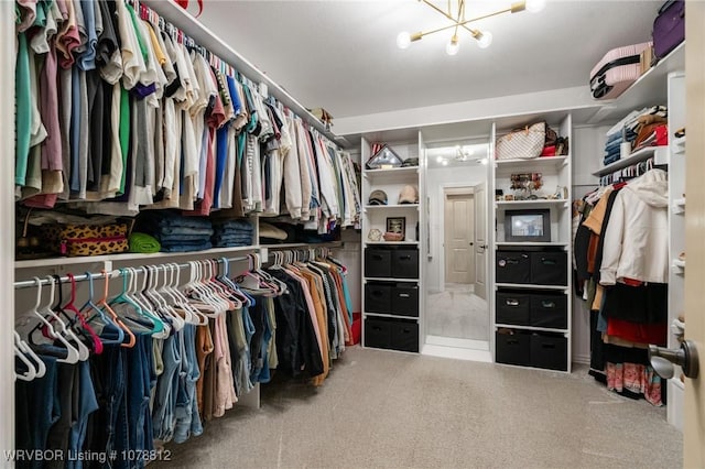 spacious closet with carpet flooring and a chandelier