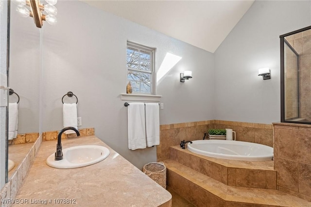 bathroom featuring tiled tub, vaulted ceiling, and vanity