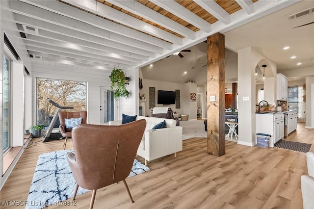 living room featuring beamed ceiling, sink, and light hardwood / wood-style floors