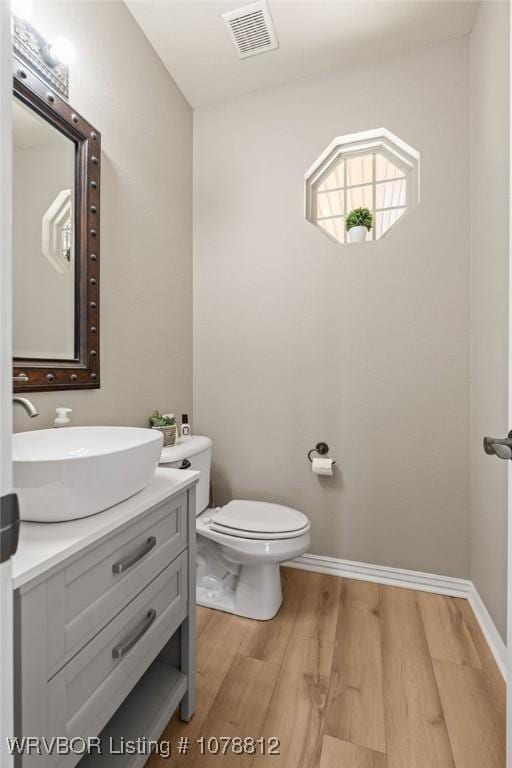 bathroom with hardwood / wood-style flooring, vanity, and toilet