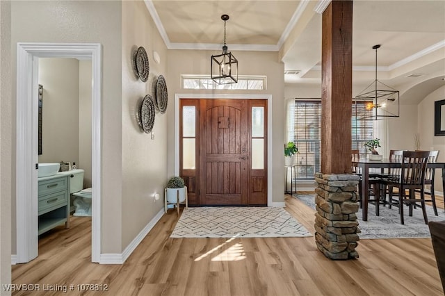 foyer entrance featuring crown molding, a notable chandelier, and light wood-type flooring