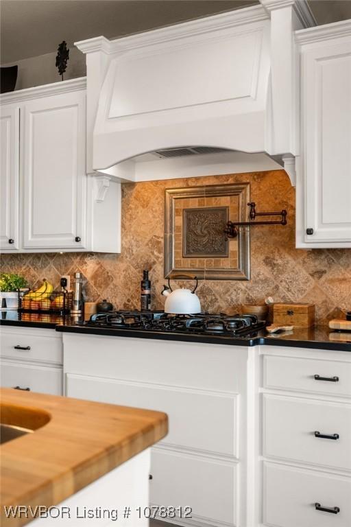 kitchen with white cabinetry, decorative backsplash, black gas stovetop, and premium range hood