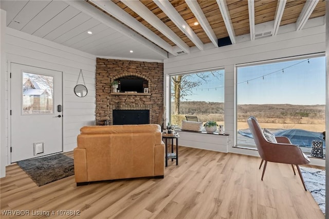 living room featuring beam ceiling, plenty of natural light, wood walls, and light wood-type flooring