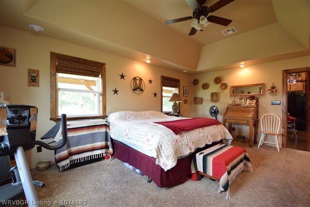 carpeted bedroom featuring a tray ceiling and ceiling fan