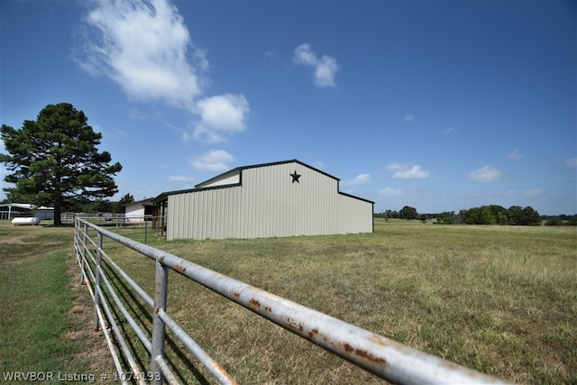 view of side of home featuring an outbuilding, a rural view, and a lawn