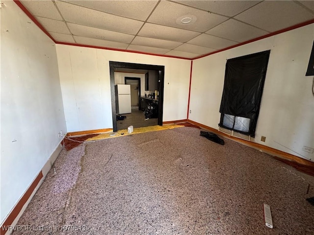 carpeted empty room with a drop ceiling and baseboards