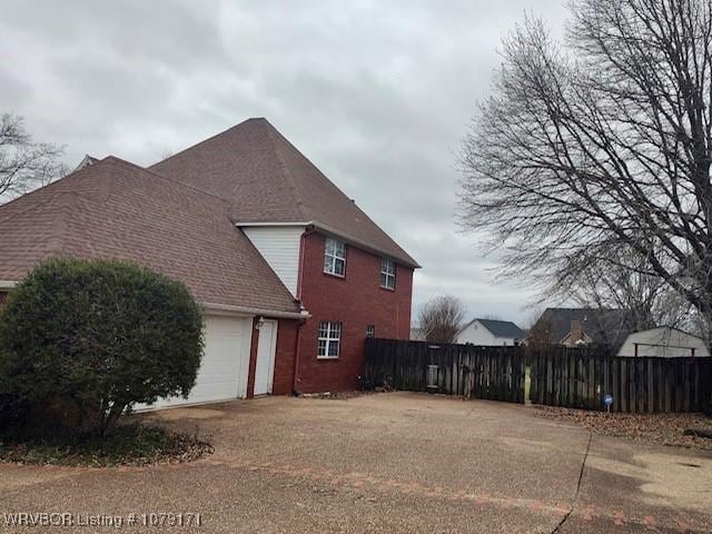 view of home's exterior with dirt driveway, fence, and an attached garage