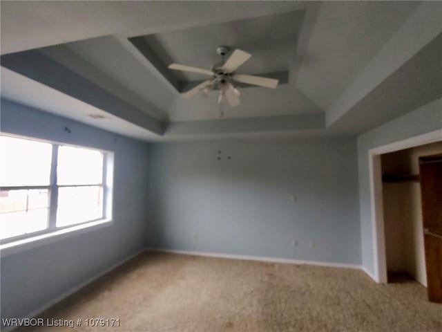 interior space with a ceiling fan, a tray ceiling, and baseboards