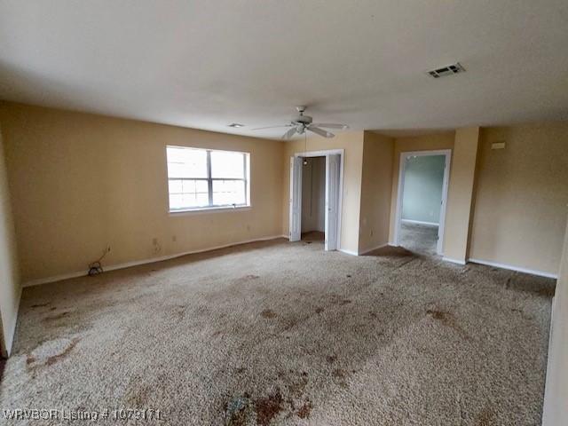 spare room with light carpet, ceiling fan, visible vents, and baseboards