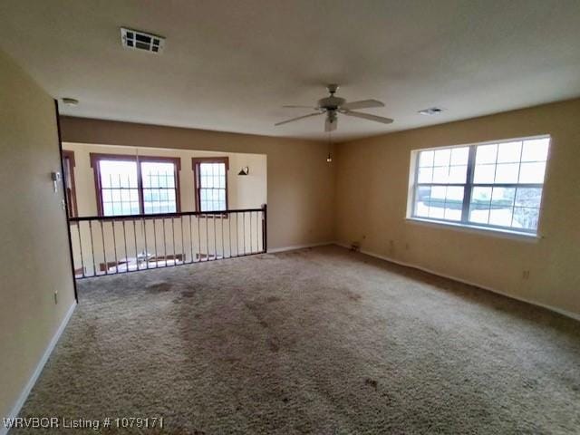 empty room featuring carpet floors, visible vents, baseboards, and a ceiling fan