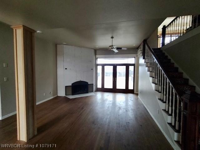 unfurnished living room featuring french doors, dark wood-type flooring, stairway, and baseboards