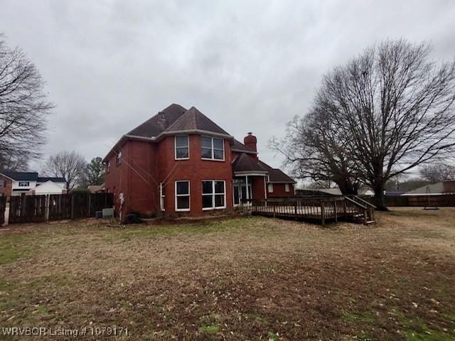 back of house with a chimney, fence, a deck, and a yard