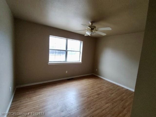 empty room with a ceiling fan, baseboards, and wood finished floors