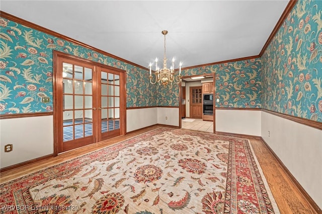 2017 S 70th St, Fort Smith, AR 72903 - unfurnished dining area featuring a wainscoted wall, a chandelier, wallpapered walls, french doors, and wood finished floors