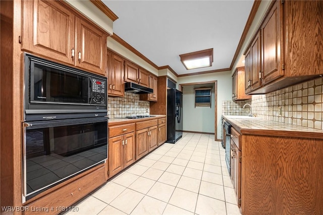 2017 S 70th St, Fort Smith, AR 72903 - kitchen featuring black appliances, under cabinet range hood, tile countertops, light tile patterned floors, and a sink