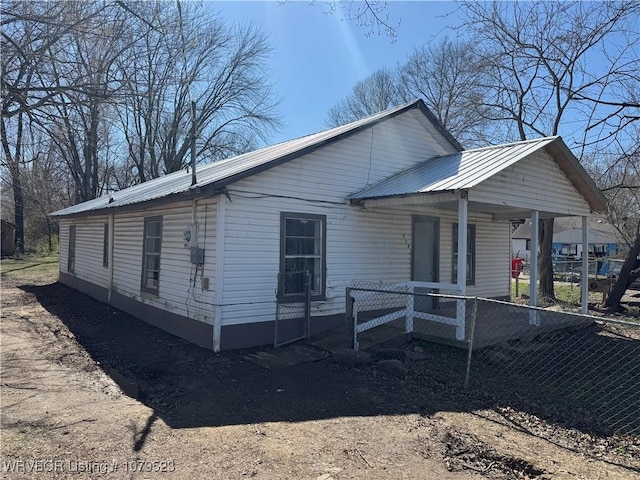 view of side of property featuring metal roof, a porch, and fence