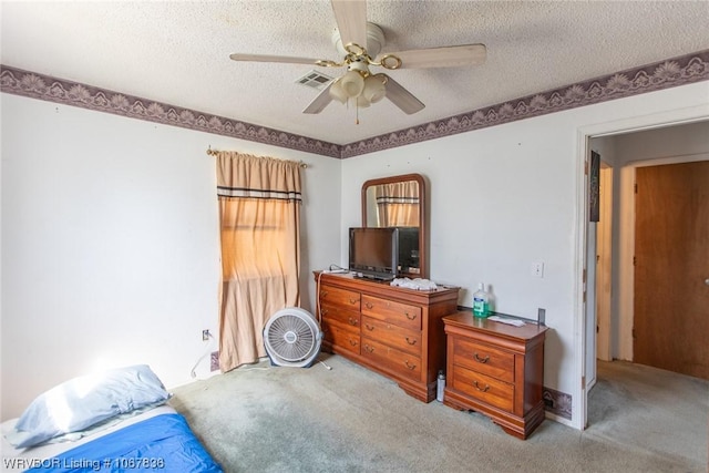 bedroom with ceiling fan, light colored carpet, and a textured ceiling