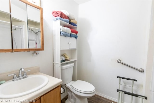 bathroom with a shower, hardwood / wood-style floors, vanity, and toilet