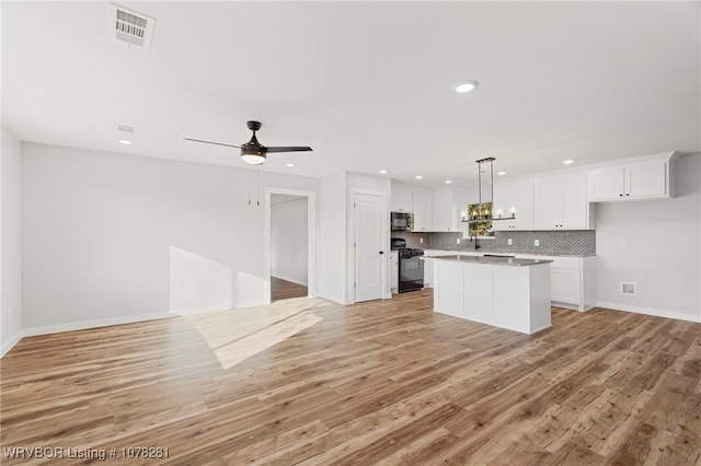 kitchen featuring light wood-type flooring, black range with gas stovetop, ceiling fan, white cabinets, and a center island