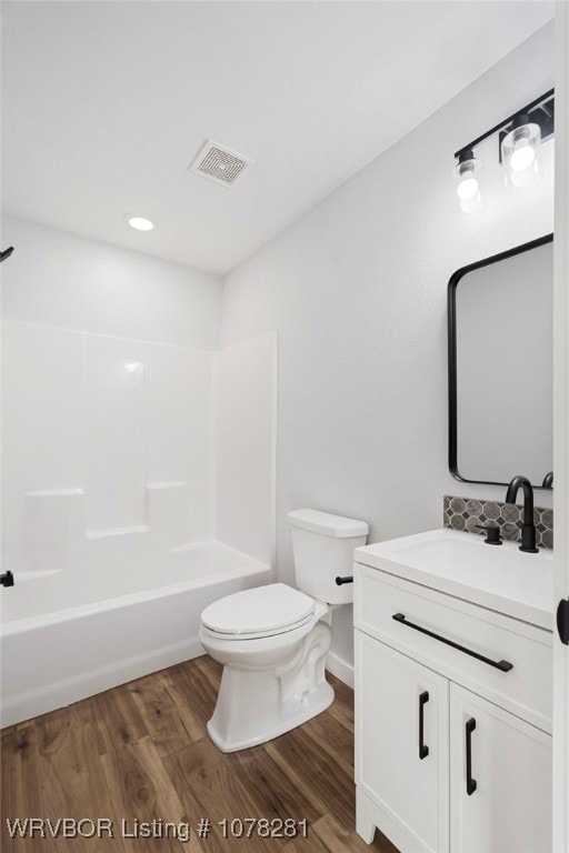 full bathroom with hardwood / wood-style flooring, vanity, shower / bathtub combination, and toilet