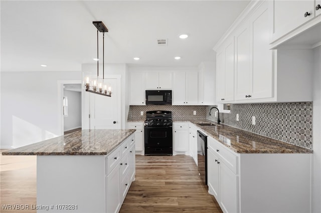 kitchen with black appliances, a kitchen island, white cabinetry, and sink