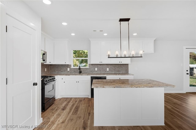 kitchen featuring a center island, pendant lighting, white cabinets, and black appliances