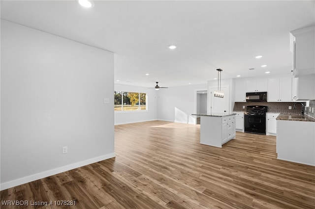 kitchen with ceiling fan, black appliances, white cabinets, a center island, and hanging light fixtures