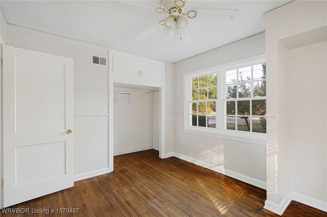 unfurnished bedroom with a closet, visible vents, dark wood-type flooring, and baseboards