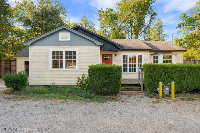 view of front of property with a shingled roof, a wooden deck, and fence