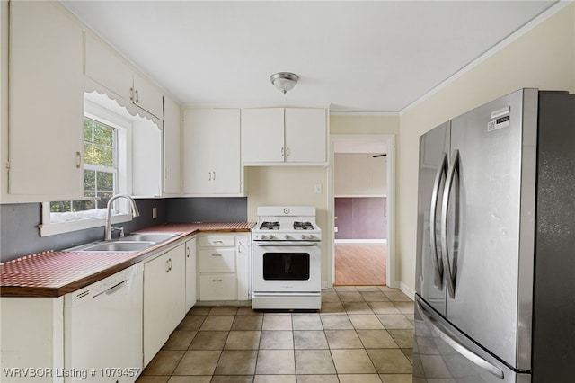 kitchen with crown molding, light tile patterned floors, white appliances, white cabinetry, and a sink