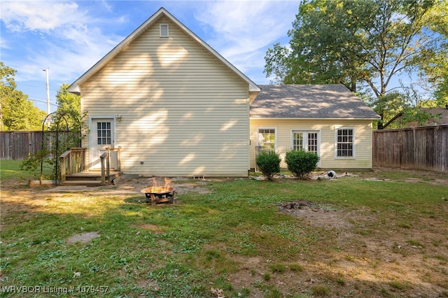 rear view of house featuring a lawn, a fire pit, and fence