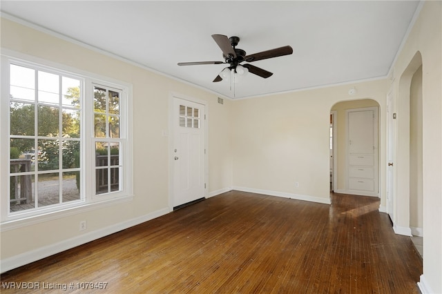 spare room with baseboards, arched walkways, wood-type flooring, and crown molding