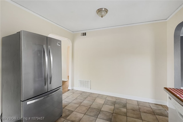 kitchen with crown molding, visible vents, arched walkways, and freestanding refrigerator